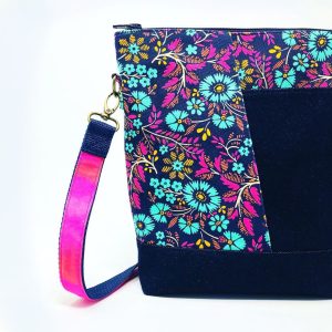 a handmade denim teloujay crossbody bag featuring a modern floral design with hot pink and teal flowers.